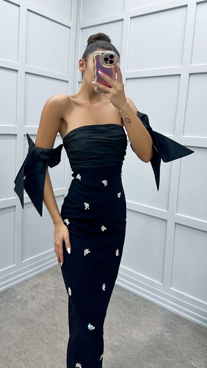 فستان أسود بدون حمالات بتفاصيل على الأكمام ومزين بأحجار الراين