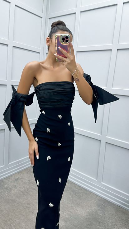 فستان أسود بدون حمالات بتفاصيل على الأكمام ومزين بأحجار الراين