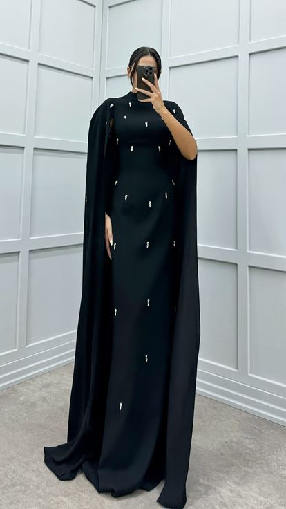 فستان أسود مزين بتفاصيل مرصعة بالأحجار على الأكمام
