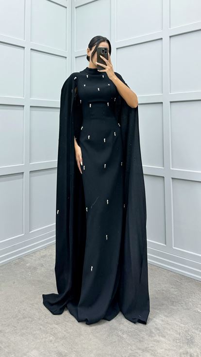 فستان أسود مزين بتفاصيل مرصعة بالأحجار على الأكمام