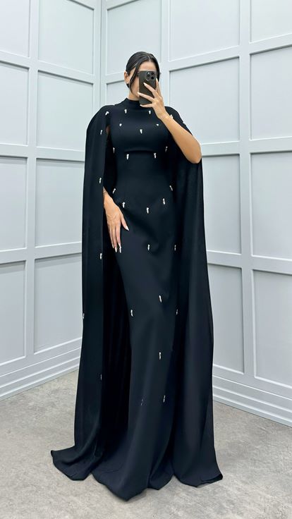 فستان أسود مزين بتفاصيل مرصعة بالأحجار على الأكمام