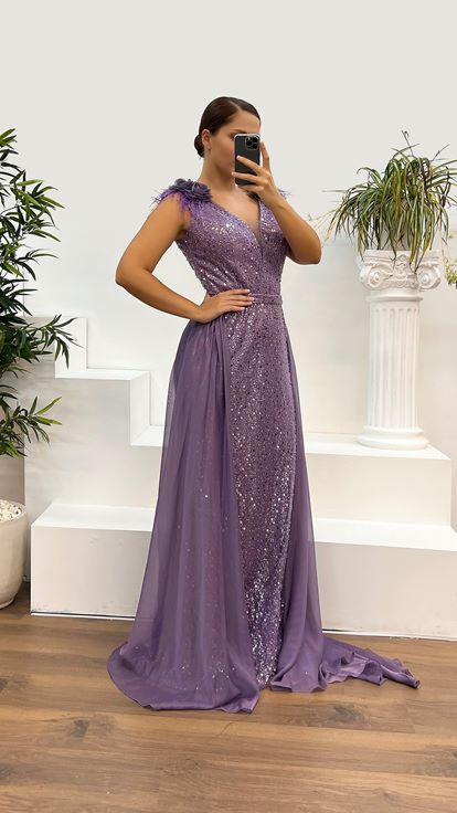 فستان سهرة أرجواني بمقاسات كبيرة مزين بتفاصيل الورد وتطريزات الريش على الكتفين