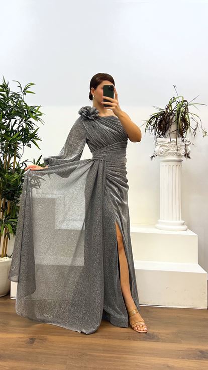 فستان سهرة فضي لامع بمقاسات كبيرة، بأكمام واحدة وتفاصيل ثنيات أنيقة 