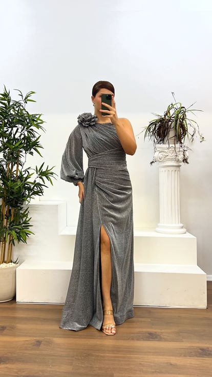 فستان سهرة فضي لامع بمقاسات كبيرة، بأكمام واحدة وتفاصيل ثنيات أنيقة 