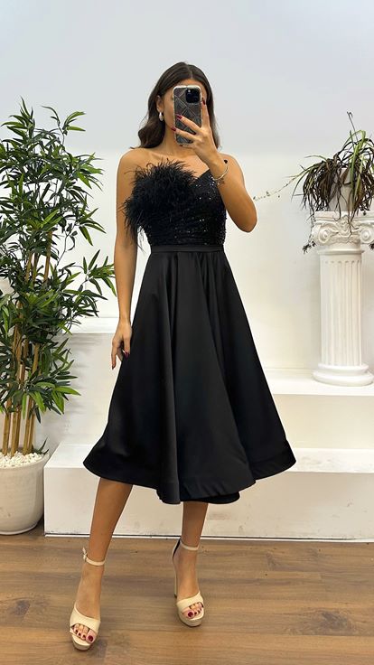 Vestido de noche negro con detalle de plumas y largo a media pierna