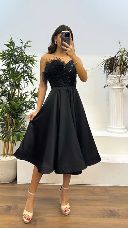 Vestido de noche negro con detalle de plumas y largo a media pierna