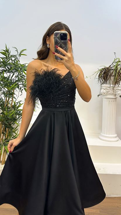 Vestido de noche negro con detalle de plumas y largo a media pierna