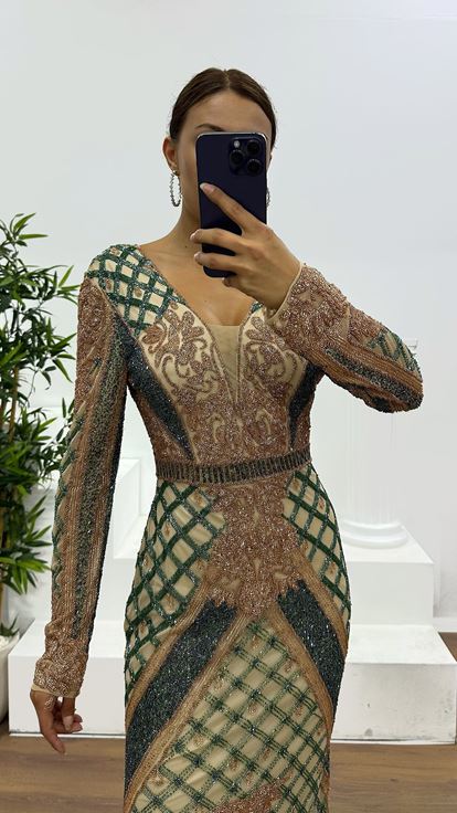 فستان سهرة كريمي اللون بياقة على شكل حرف V وتفاصيل خلفية مطرزة يدوياً