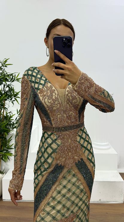 فستان سهرة كريمي اللون بياقة على شكل حرف V وتفاصيل خلفية مطرزة يدوياً