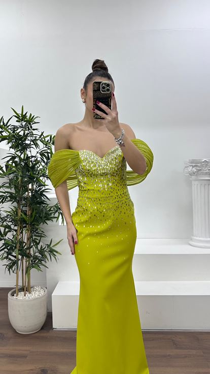 فستان سهرة بلون الفستق الأخضر بياقة قارب وتفاصيل من الأحجار