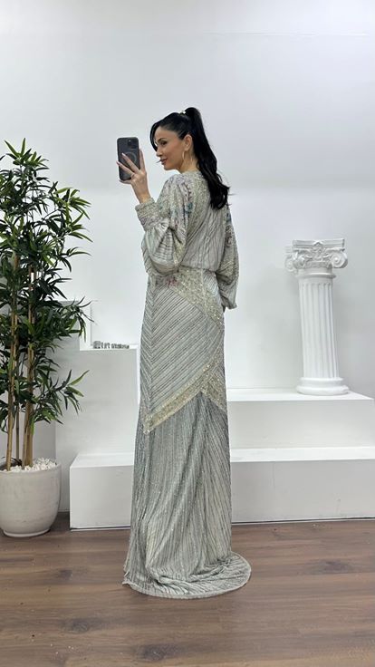 فستان سهرة فضي اللون بياقة على شكل حرف V عميقة وأكمام واسعة مزينة بكشكشة