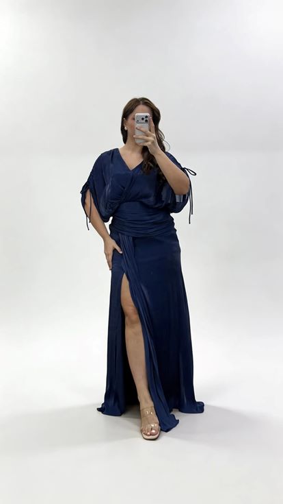 فستان سهرة أزرق داكن بياقة على شكل حرف V وكسرات ومقاسات كبيرة مع تفاصيل تجميعية