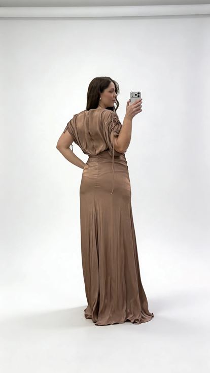 فستان سهرة بني اللون بمقاسات كبيرة، بياقة على شكل حرف V وكسرات وتفاصيل مكشكشة 