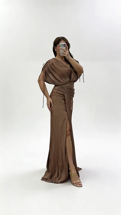 فستان سهرة بني اللون بمقاسات كبيرة، بياقة على شكل حرف V وكسرات وتفاصيل مكشكشة 