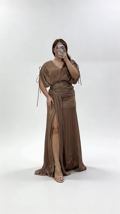 فستان سهرة بني اللون بمقاسات كبيرة، بياقة على شكل حرف V وكسرات وتفاصيل مكشكشة 