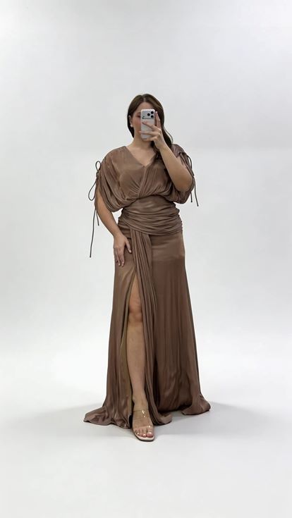 فستان سهرة بني اللون بمقاسات كبيرة، بياقة على شكل حرف V وكسرات وتفاصيل مكشكشة 