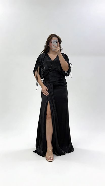 فستان سهرة أسود بمقاسات كبيرة، بياقة على شكل حرف V وثنيات وتفاصيل مكشكشة