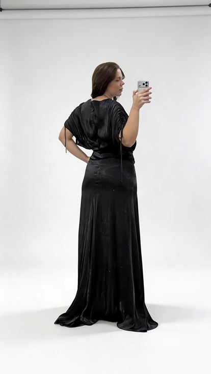 فستان سهرة أسود بمقاسات كبيرة، بياقة على شكل حرف V وثنيات وتفاصيل مكشكشة