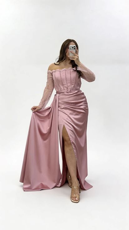 فستان سهرة من الساتان بمقاسات كبيرة، بلون وردي فاتح، بياقة قارب وحزام، وتفاصيل من الدانتيل على الأكمام 