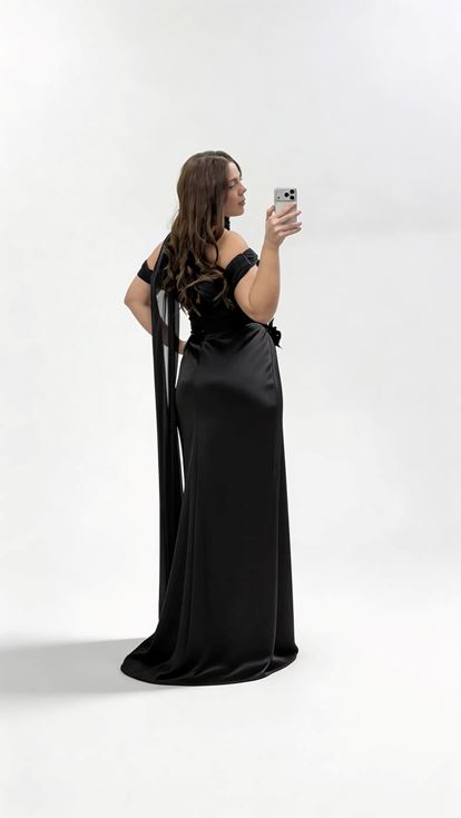 فستان سهرة أسود بمقاسات كبيرة مزين بشال طويل، وتطريزات زهرية، وربطة عنق 