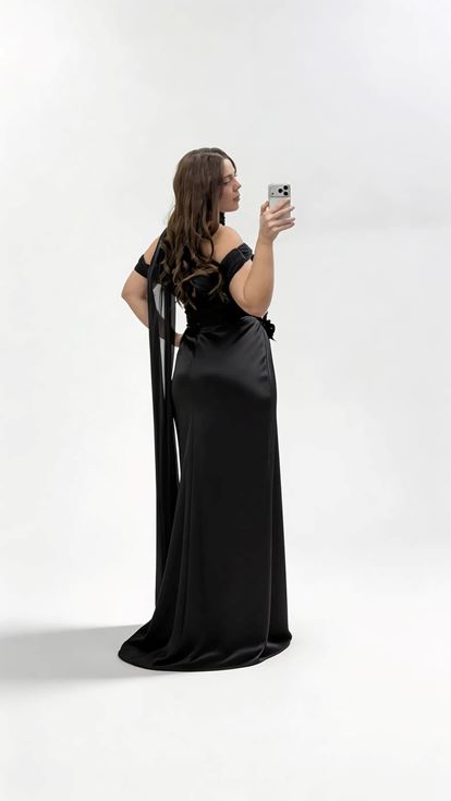 فستان سهرة أسود بمقاسات كبيرة مزين بشال طويل، وتطريزات زهرية، وربطة عنق 